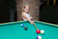 Little beautiful blond girl learns to play billiards, pool, snooker, Russian pyramid in kid`s club Royalty Free Stock Photo