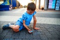 Little beautiful boy draws with chalk on the pavement