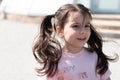 Little beautiful cheerful girl in glasses with pigtails runs down the street Royalty Free Stock Photo