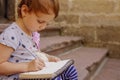 Little beautiful child girl writing a letter.