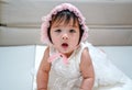 Little Baby Princess girl wear white dress with whit hood lying down on pad floor. Looking at camera Royalty Free Stock Photo