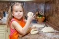 Little beautiful cute girl in orange apron smiling and making homemade pizza, roll the dough at home kitchen. Concept happy family Royalty Free Stock Photo