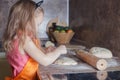 Little beautiful cute girl in orange apron smiling and making homemade pizza, roll the dough at home kitchen. Concept happy family Royalty Free Stock Photo