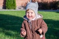 Little beautiful girl baby coat, hat and jeans playing in the park walking on green grass doing their first steps smiling and enjo Royalty Free Stock Photo