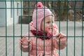 Little beautiful girl baby crying with tears in his eyes and a sad, sad emotions shut down as a punishment for a fence of metal la