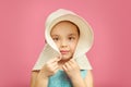 Little beautiful girl in beach hat and blue dress on pink isolated background. Royalty Free Stock Photo