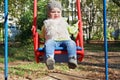 Little beautiful girl in blue jeans swings Royalty Free Stock Photo
