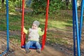 Little beautiful girl in blue jeans swings Royalty Free Stock Photo