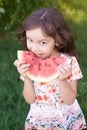 Little beautiful girl. Bright green grass. Juicy, delicious, red