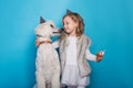 Little beautiful girl with dog celebrate birthday. Friendship. Love. Cake with candle. Studio portrait over blue background Royalty Free Stock Photo