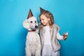 Little beautiful girl with dog celebrate birthday. Friendship. Love. Cake with candle. Studio portrait over blue background Royalty Free Stock Photo