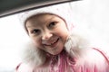 Little beautiful girl dressed in a warm pink jacket and knitted hat, frosty in winter, smiles and looks in the car Royalty Free Stock Photo