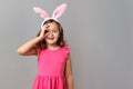 Little beautiful girl in the ears of the Easter bunny, shows ok gesture and looks through her fingers. Royalty Free Stock Photo