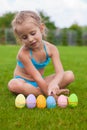 Little beautiful girl finds Easter eggs on green