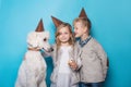 Little beautiful girl and handsome boy with dog celebrate birthday. Friendship. Family. Studio portrait over blue background Royalty Free Stock Photo