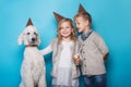 Little beautiful girl and handsome boy with dog celebrate birthday. Friendship. Family. Studio portrait over blue background Royalty Free Stock Photo