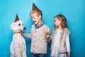 Little beautiful girl and handsome boy with dog celebrate birthday. Friendship. Family. Studio portrait over blue background Royalty Free Stock Photo