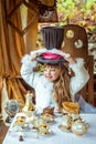 An little beautiful girl holding cylinder hat with ears like a rabbit over head at the table Royalty Free Stock Photo