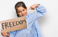 Little beautiful girl holding freedom banner pointing finger to one self smiling happy and proud