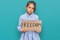 Little beautiful girl holding freedom banner thinking attitude and sober expression looking self confident