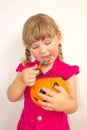 Little beautiful girl holding pumpkin with sweets in hands, on Halloween. Royalty Free Stock Photo