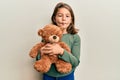 Little beautiful girl hugging teddy bear making fish face with mouth and squinting eyes, crazy and comical