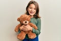 Little beautiful girl hugging teddy bear smiling and laughing hard out loud because funny crazy joke Royalty Free Stock Photo