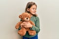 Little beautiful girl hugging teddy bear smiling looking to the side and staring away thinking Royalty Free Stock Photo