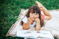 Little beautiful girl lie on grass with book looking at camera