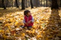 Little beautiful girl loves autumn, walks in autumn forest and smiles