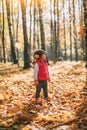 Little beautiful girl loves autumn, walks in autumn forest