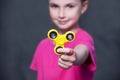 Little beautiful girl in pink t-shirt is playing yellow spinner in hand