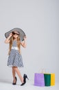 Little beautiful girl in a polka dot dress and hat, with shopping bags on a white background. Shopping Royalty Free Stock Photo