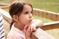 Little beautiful girl with a ponytail leans on the handrail puffing out her cheeks Royalty Free Stock Photo