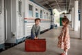 Little beautiful girl in retro dress says goodbye at the station with a little boy in vintage clothes with retro suitcase Royalty Free Stock Photo