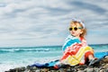 Little beautiful girl sit wrapped in beach towel over the sea Royalty Free Stock Photo