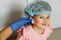 Little beautiful girl smiles and looks into the camera. Waiting for the doctor to clean the ear and make a puncture Royalty Free Stock Photo