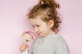 Little beautiful girl sniffs bouquet of daisies