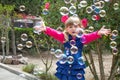 Little beautiful girl walks with a soft toy in their hands. On open air.Little girl playing with soap bubbles in the garden Royalty Free Stock Photo