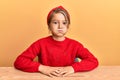 Little beautiful girl wearing casual clothes sitting on the table puffing cheeks with funny face Royalty Free Stock Photo