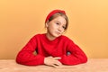 Little beautiful girl wearing casual clothes sitting on the table smiling looking to the side and staring away thinking Royalty Free Stock Photo