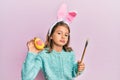 Little beautiful girl wearing cute easter bunny ears holding colored egg looking at the camera blowing a kiss being lovely and Royalty Free Stock Photo