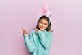 Little beautiful girl wearing cute easter bunny ears smiling and looking at the camera pointing with two hands and fingers to the Royalty Free Stock Photo