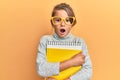 Little beautiful girl wearing glasses and holding books afraid and shocked with surprise and amazed expression, fear and excited Royalty Free Stock Photo