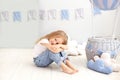 Little beautiful girl in a white T-shirt and jeans sits on the background of a decorative balloon. The child plays in the children