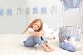 Little beautiful girl in a white T-shirt and jeans sits on the background of a decorative balloon. The child plays in the children