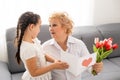 Little beautiful granddaughter gives her grandmother a bouquet of pink tulips. The concept of family, respect Royalty Free Stock Photo