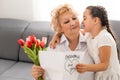 Little beautiful granddaughter gives her grandmother a bouquet of pink tulips. The concept of family, respect Royalty Free Stock Photo