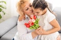 Little beautiful granddaughter gives her grandmother a bouquet of pink tulips. The concept of family, respect Royalty Free Stock Photo