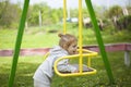 Little beautiful red-haired girl hung on a swing, baby plays on a swing on the playground Royalty Free Stock Photo